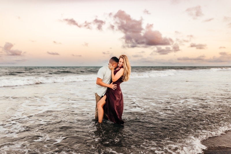 Family Photographer, husband and wife embrace in the beach tides